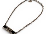 a close up of a necklace on a white surface with a chain