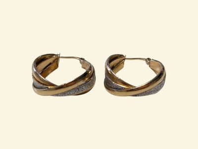 a pair of gold toned hoop earrings sitting on top of a white surface
