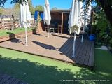 a wooden deck with umbrellas and chairs in the yard