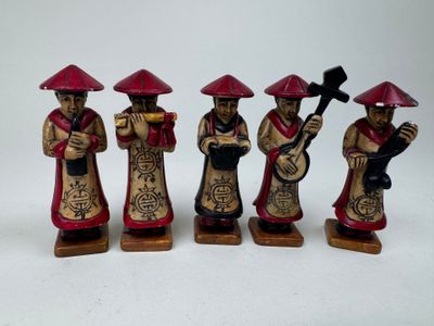 quatre figurines représentant des hommes asiatiques coiffés de chapeaux rouges et tenant des instruments