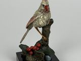 statue représentant un oiseau perché sur une branche ornée de baies