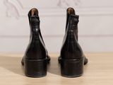 the back of a pair of black leather ankle boots on a wooden table