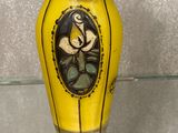 a yellow vase with a picture of a woman on it