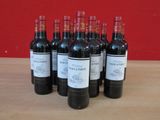 six bouteilles de vin rouge sont alignées sur une table en bois