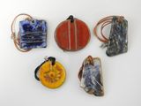 six pendentifs artisanaux en verre et en cuir sur un fond blanc