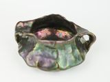 a purple and green bowl with handles on a white surface