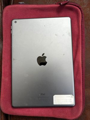 un iPad d'Apple posé sur un sac rouge, lui-même posé sur un canapé marron