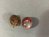 two red and gold badges on a white surface