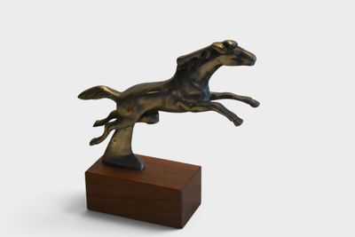 statue of a running horse on a wooden base on a white background
