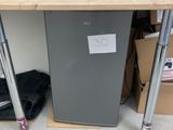 a small refrigerator sitting under a desk in a room