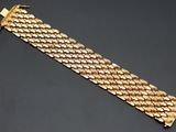 gros plan d'un bracelet en or sur une surface noire