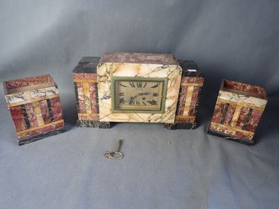 une petite horloge posée sur une table, à côté d'autres objets