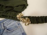 a belt with a gold flower on it next to a pair of jeans