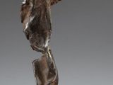 statue en bronze représentant un garçon, posée sur un socle, sur une surface blanche