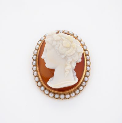 un gros plan sur une broche représentant une femme portant des perles