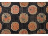 an old black and orange rug with circles and flowers on it