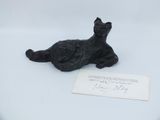 a black cat figurine sitting on a white surface next to a piece of paper