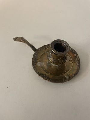un petit bougeoir en métal posé sur une table blanche