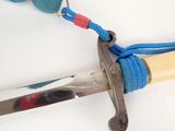 a close up of a knife with a blue string on it