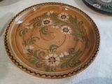 a brown plate with flowers on it sitting on a table