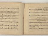 an open book with music notes on it sitting on a table