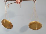 a hand holding a pair of scales above a wooden box