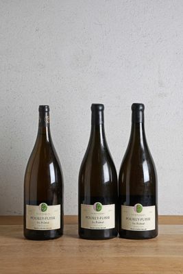 trois bouteilles de vin posées sur une table en bois, à côté d'une bouteille de vin