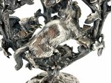a silver vase with a bird on it on a stand