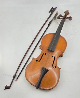 an old violin sitting on top of a white table next to a bow