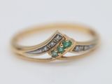 a close up of a gold ring with a green and white diamond