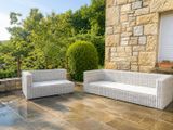 un canapé blanc et deux fauteuils posés sur une terrasse