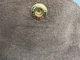 someone is holding a purse with a gold button on top of it