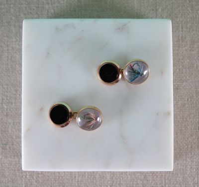 une paire de boucles d'oreilles noires et blanches posées sur une dalle de marbre