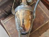 un vase en argent muni d'une anse, posé sur une table