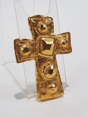 a gold cross on a clear stand on a white surface