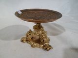une assiette en or posée sur un socle, sur une nappe blanche