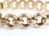 an image of a gold bracelet on a white surface