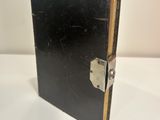 an old black book with a lock on it sitting on a table