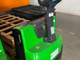 un chariot élévateur vert garé dans un entrepôt