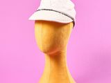 un chapeau blanc posé sur la tête d'un mannequin, sur fond rose