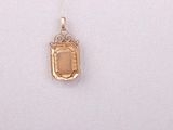 a gold necklace that has a picture of a suitcase on it