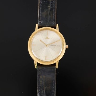 un gros plan d'une montre en or avec un bracelet en cuir noir