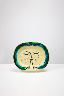 une assiette verte et blanche sur laquelle est peint un visage
