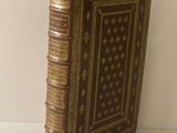 un vieux livre posé sur une table blanche à côté d'un mur blanc