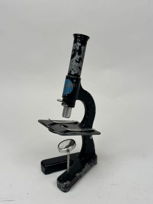 Gros plan sur un microscope posé sur une surface blanche, avec un fond blanc