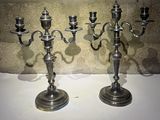 deux chandeliers en argent posés sur une table près d'un mur