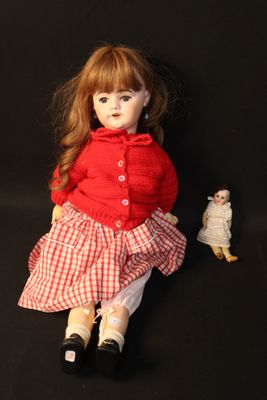 a doll that is sitting next to a doll on a black background