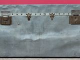 une vieille valise posée par terre devant un mur rose