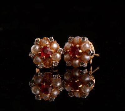 pair of pearl and ruby earrings on a black surface