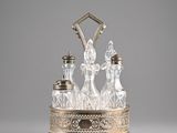 an antique silver and glass decanter with four bottles on a stand